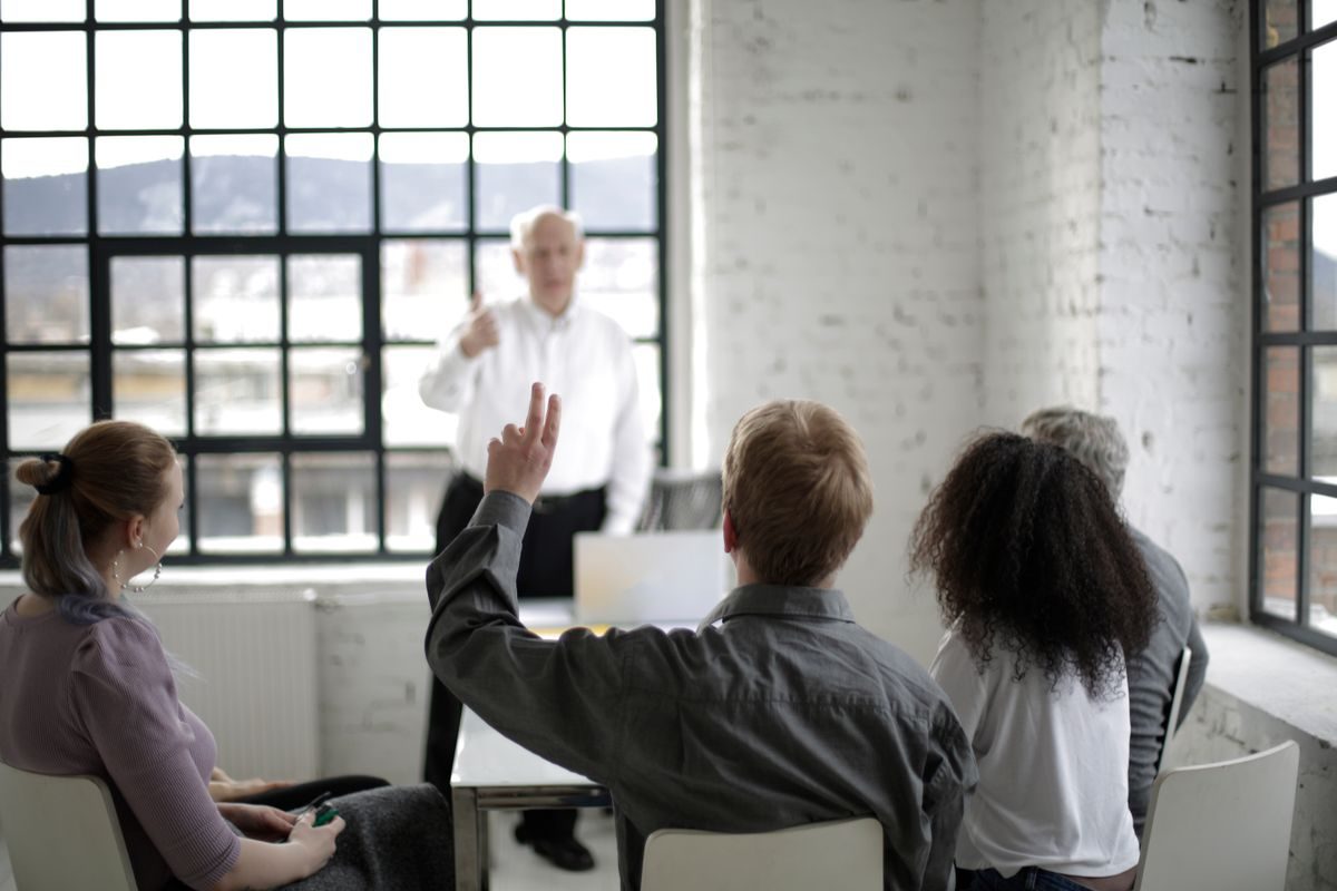 A community group meeting in a bright room, one member raising a hand