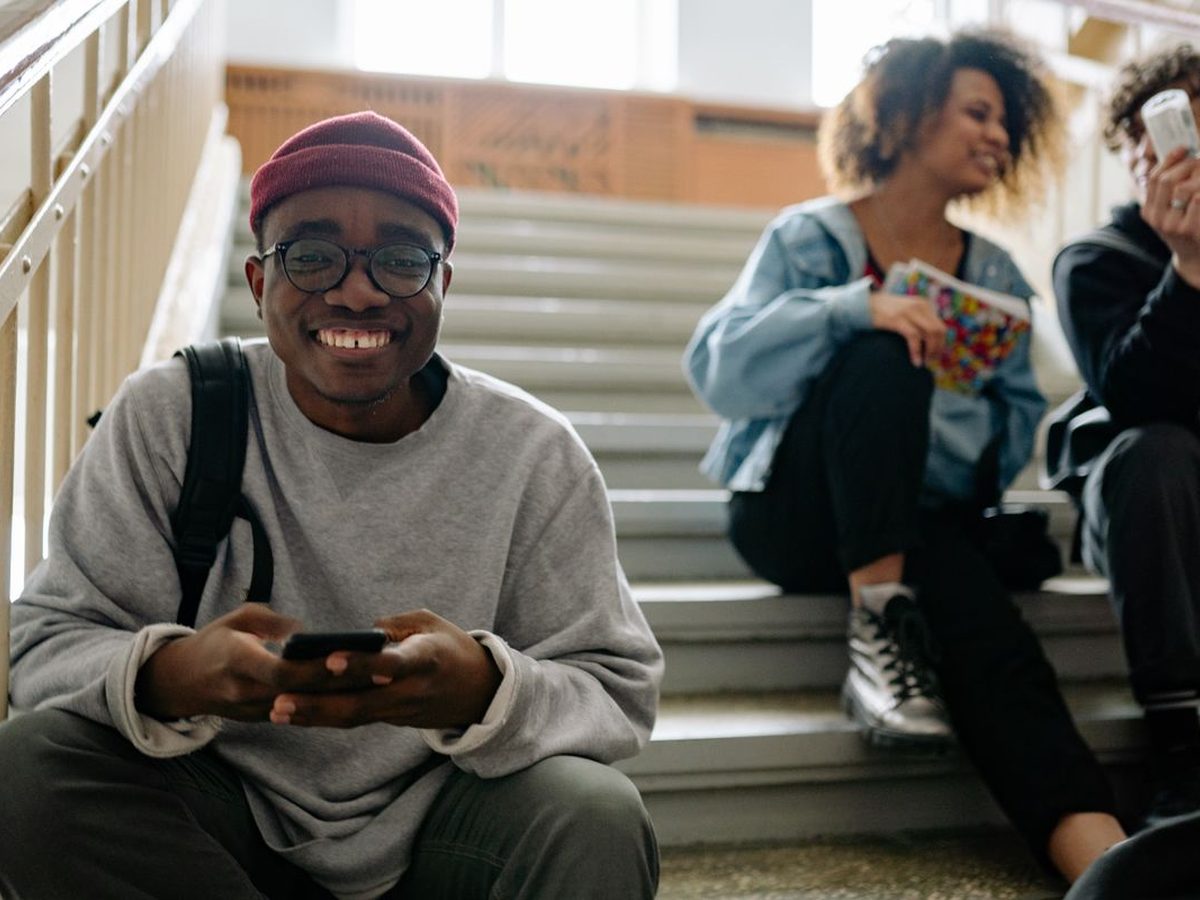 A student on a staircase voting on his phone, classmates behind