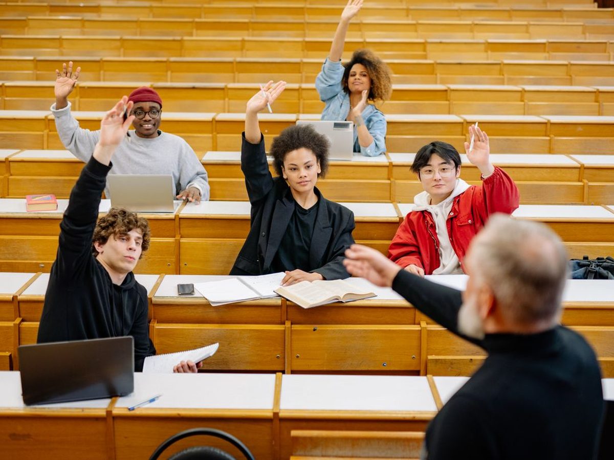 Students in a lecture theatre raising their hands