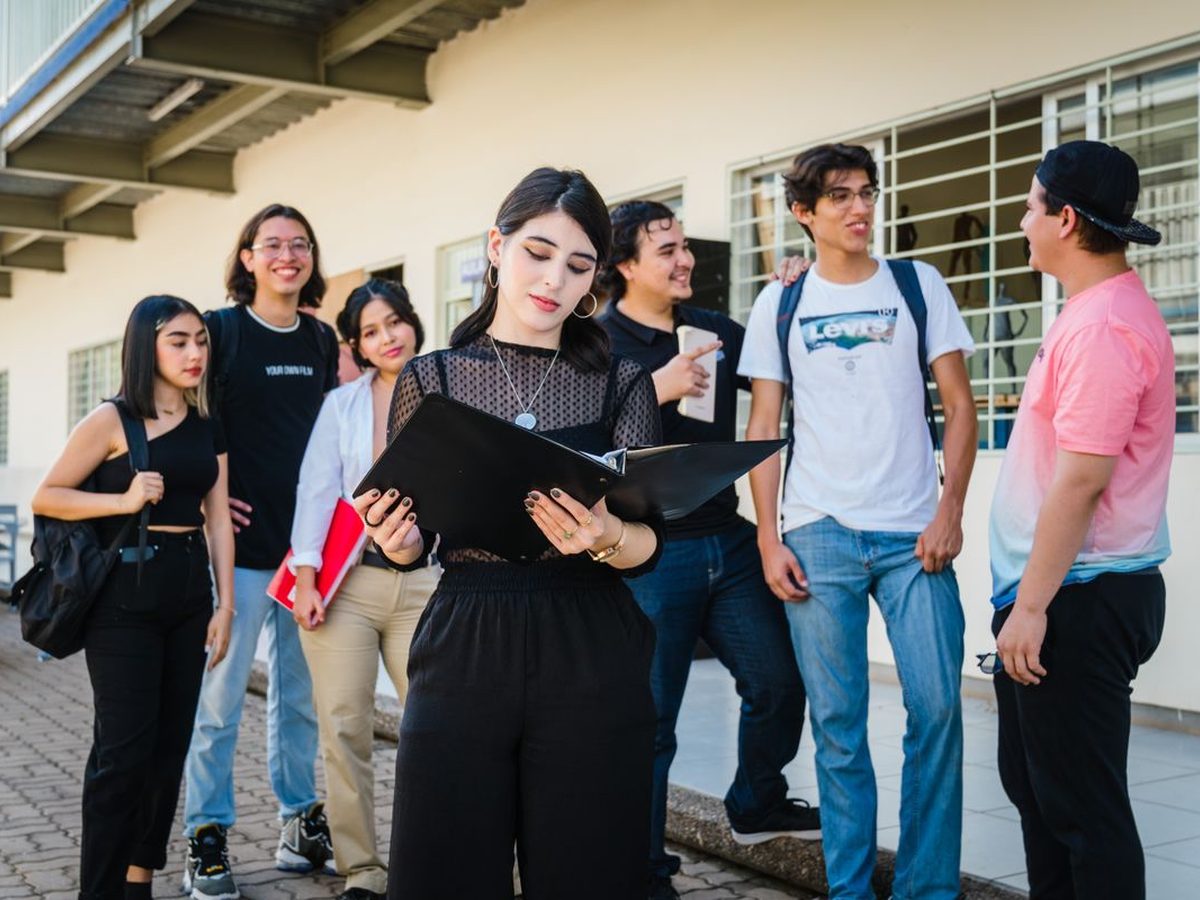A student society gathered outside, one reading from a folder